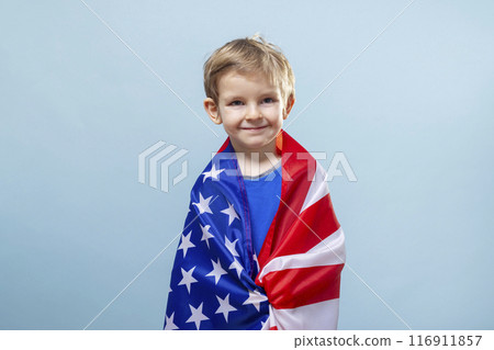 Boy wrapped in American flag on blue background Boy wrapped in American flag on blue background 116911857