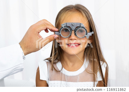 Doctor holding special eye equipment examinating girl's eyes 116911862