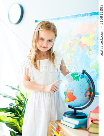 Little schoolage girl pointing on the globe in the sunshine classroom 116911892