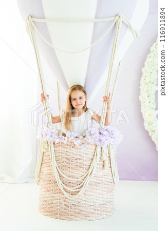 Little blond girl in a white dress standing in the beautiful decorative air balloon 116911894