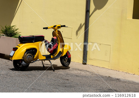 Vintage Yellow Scooter Against Yellow Wall Vintage Yellow Scooter Against Yellow Wall 116912618