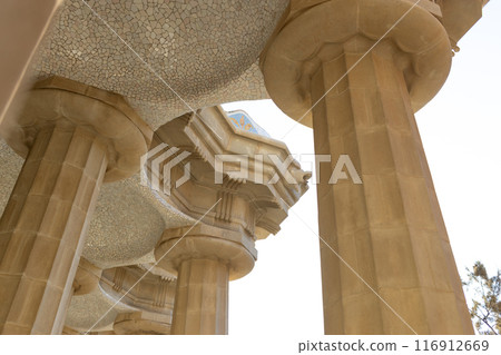 Columns with fragments of tiles and ceiling with small domes, hypostyle hall in Park Guell. Barcelona, Spain 116912669