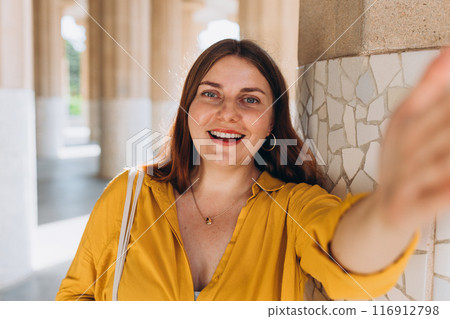 Beautiful female in Gaudi garden, Spain, Barcelona. Young traveling woman taking selfie outdoors. Concept of travel, tourism and vacation in city. Hypostyle hall Beautiful female in Gaudi garden, Spain, Barcelona. Young traveling woman taking selfie outdoors. Concept of travel, tourism and vacation in city. Hypostyle hall 116912798