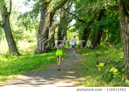 Rear view on active young woman running during the triathlon competition. Rear view on active young woman running during the triathlon competition. 116913342