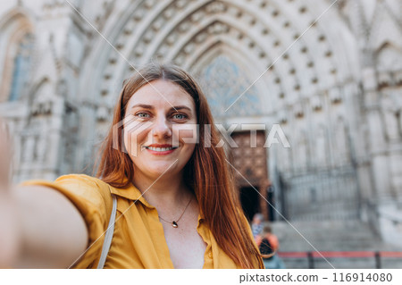 Young traveling woman taking selfie near The Cathedral of the Holy Cross and Saint Eulalia. Concept of travel, tourism and vacation in city. Young traveling woman taking selfie near The Cathedral of the Holy Cross and Saint Eulalia. Concept of travel, tourism and vacation in city. 116914080