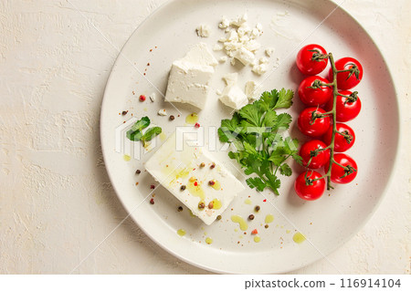 feta cheese, for salads, with cherry , green butter, greens, on a white plate, appetizer, top view, close-up, feta cheese, for salads, with cherry , green butter, greens, on a white plate, appetizer, top view, close-up, 116914104