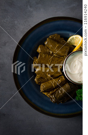Dolma, cabbage rolls, grape leaves with filling, white sauce, lemon and herbs, rustic, selective focus, no people, 116914240