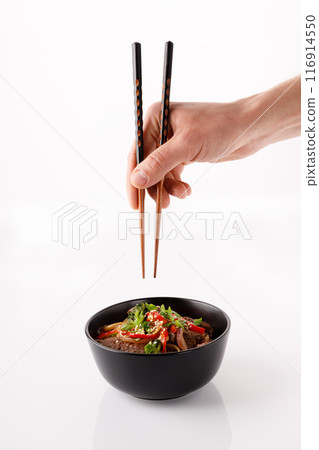 Classic Japanese udon stir fry wheat noodles with wok-style vegetables and teriyaki sauce, sesame, onions, green beans, paprika, broccoli, cucumber. On a black plate. 116914550