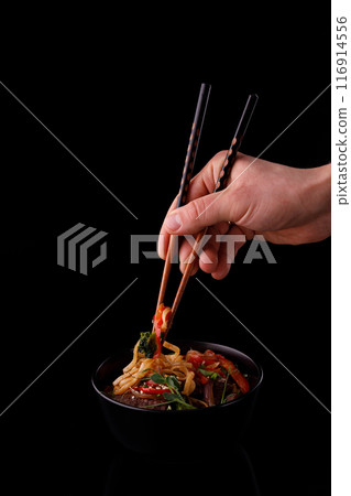 Stir fry noodles with vegetables and shrimps in black bowl. Slate background. Top view. Copy space. 116914556