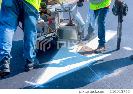 An airbrush machine is used to apply signs after asphalt has been laid on road An airbrush machine is used to apply signs after asphalt has been laid on road 116915763