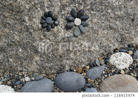 Rock garden. A flowers laid out of pebbles on a stone. 116915974