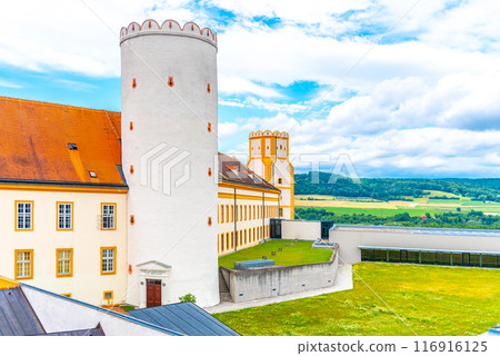 A vibrant view of Melk Abbey with its iconic yellow facade and circular tower, overlooking a scenic landscape under a partly cloudy sky. Melk, Austria A vibrant view of Melk Abbey with its iconic yellow facade and circular tower, overlooking a scenic landscape under a partly cloudy sky. Melk, Austria 116916125