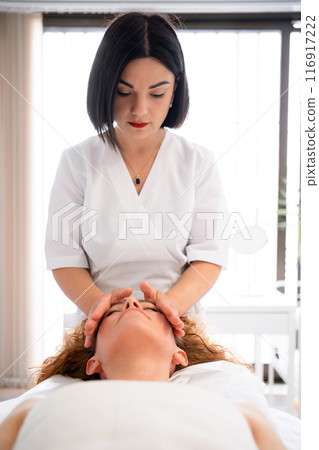 Masseur massaging relaxed woman lying on bed in Masseur massaging relaxed woman lying on bed in 116917222