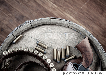Colt Revolver and gun belt with ammunition on wooden barrel. Top view. 116917363