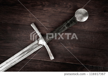 Medieval sword on wooden background. 116917367