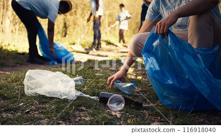 People using proper tools to clean the forest and recycle plastic waste, fighting pollution and illegal dumping. Activists volunteering to collect rubbish from the woods. Close up. Camera B. People using proper tools to clean the forest and recycle plastic waste, fighting pollution and illegal dumping. Activists volunteering to collect rubbish from the woods. Close up. Camera B. 116918040