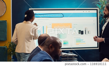 Employees team sharing insight on sales statistics in corporate briefing meeting, providing initiatives to enhance operational efficiency and agility. Group of business associates. Camera A. 116918111