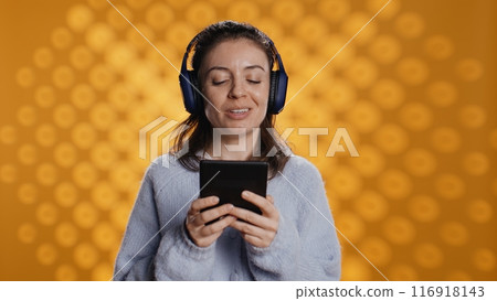 Voice actor smiling while reading ebook, portraying proud and sassy character, studio background. Woman reenacting digital novel, interpreting cheerful protagonist, reading text from tablet, camera B Voice actor smiling while reading ebook, portraying proud and sassy character, studio background. Woman reenacting digital novel, interpreting cheerful protagonist, reading text from tablet, camera B 116918143