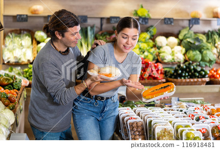 Man and woman choose papaya and roots in shop 116918481
