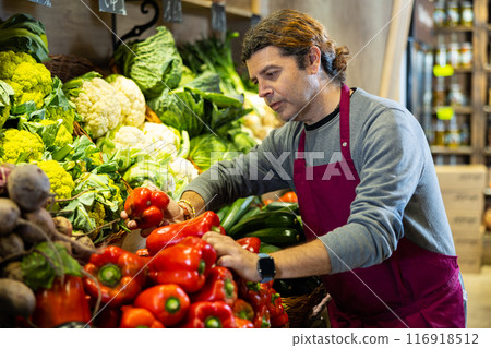 Adult man selling bell peppers in shop Adult man selling bell peppers in shop 116918512