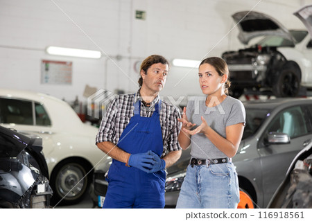 Male car repair shop worker consulting female client Male car repair shop worker consulting female client 116918561