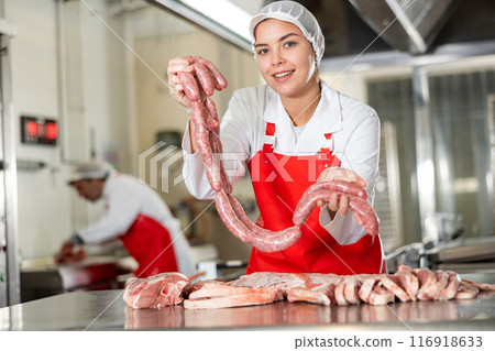 Butcher shop salesgirl offering raw pork sausages Butcher shop salesgirl offering raw pork sausages 116918633