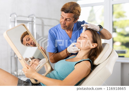 Adult male doctor examining face of female patient 116918665