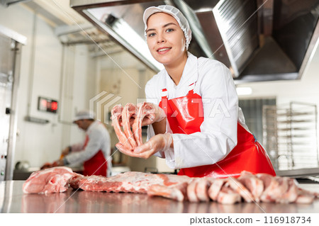 Butcher shop saleswoman showing fresh raw lamb ribs 116918734