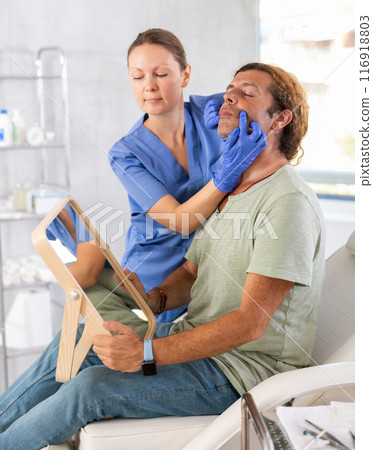 Adult female doctor examining face of male patient 116918803