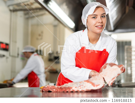 Butchery workwoman showing slab of fresh raw pork ribs 116918815