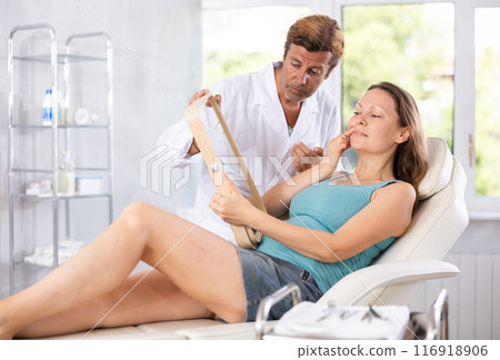 Male cosmetologist examining face of woman and planning face lifting procedures Male cosmetologist examining face of woman and planning face lifting procedures 116918906