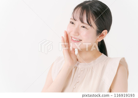 A smiling woman in her 20s touching her cheek 116919193