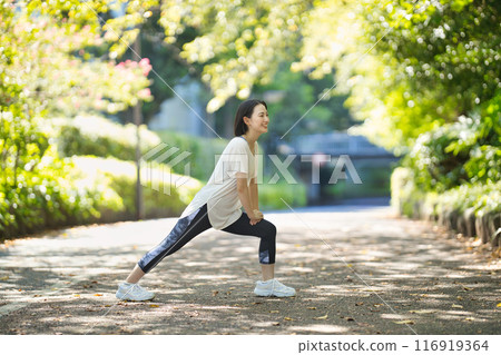 穿著運動服的微笑的年輕女子伸展身體 116919364