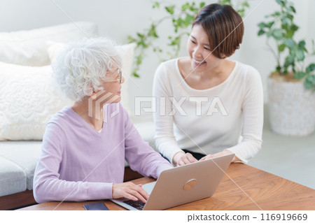 Daughter teaching her elderly mother how to use a computer (Family) 116919669
