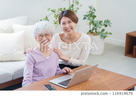 Daughter teaching her elderly mother how to use a computer (Family) 116919670