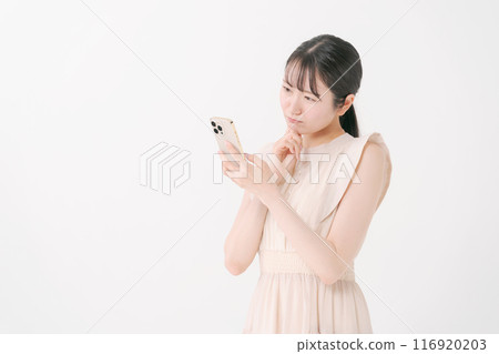 A young woman thinking while looking at her smartphone 116920203