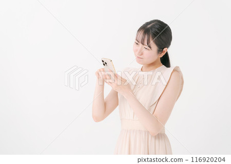 A young woman thinking while looking at her smartphone 116920204
