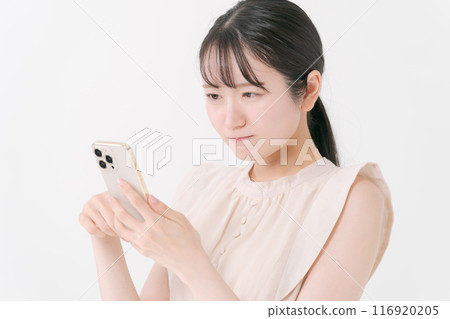 A young woman thinking while looking at her smartphone 116920205