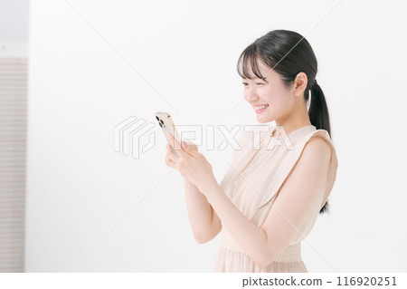 看智能手機的一個微笑的少婦 116920251