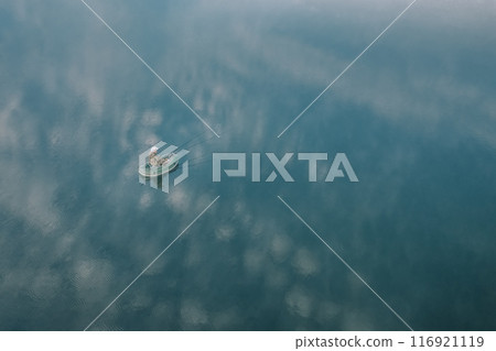 A breathtaking aerial view showcases a small boat sailing peacefully on calm and serene waters 116921119