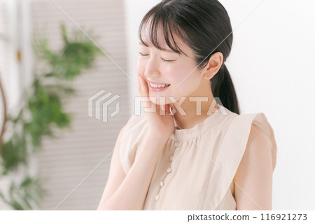 一個 20 多歲的女人摸著臉頰 116921273