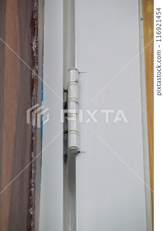 Metal door hinge close up, interior White wooden door 116921454