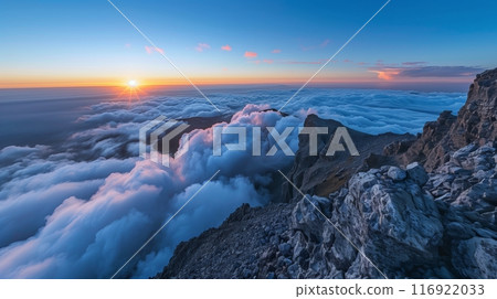 A breathtaking sunrise from a mountain peak illuminates clouds in golden glow, heralding a new day. 116922033