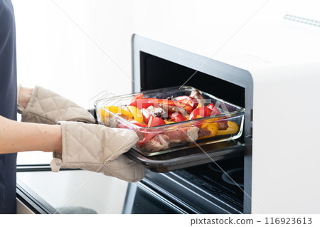 Putting grilled spare ribs and vegetables into the oven 116923613