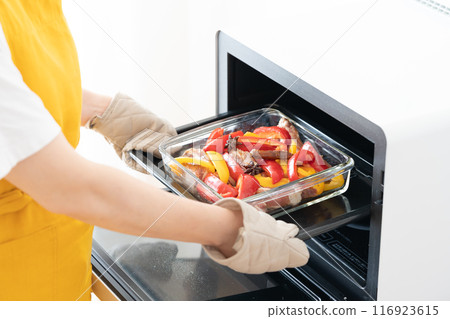 Putting grilled spare ribs and vegetables into the oven Putting grilled spare ribs and vegetables into the oven 116923615