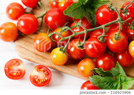 Cherry tomatoes with vines on wooden plank. 116923906