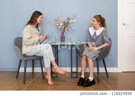 Interview preteen girl in school office. High school counselor talking to student A social worker having a conversation with a teenage girl at school Interview preteen girl in school office. High school counselor talking to student A social worker having a conversation with a teenage girl at school 116924890
