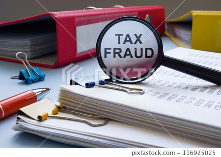 Tax fraud concept. Financial statement papers and a magnifying glass. 116925025