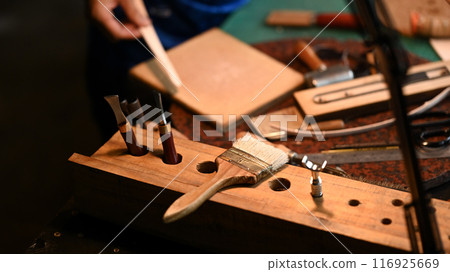 Various leather craft tools and material on a workbench. Close up shot 116925669