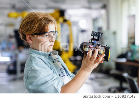 Portrait of schoolboy building robotic car in after-school robotics club. Children learning robotics in Elementary school. Science for kids. Portrait of schoolboy building robotic car in after-school robotics club. Children learning robotics in Elementary school. Science for kids. 116927142
